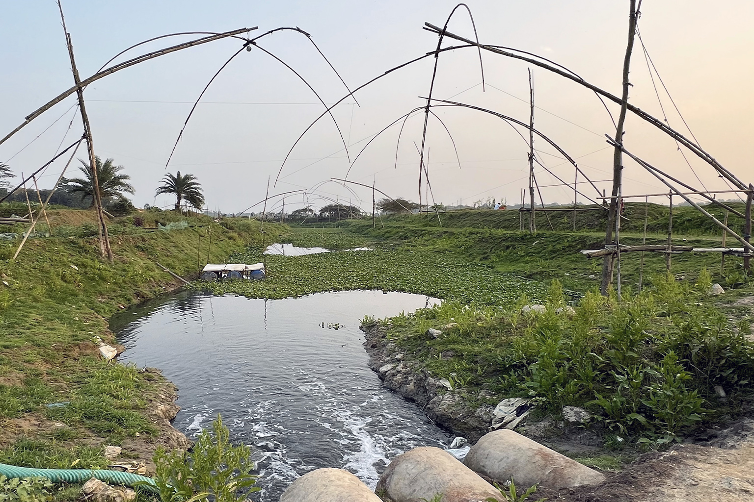 Fishing rods set in a water canal that also has industrial waste let into it.